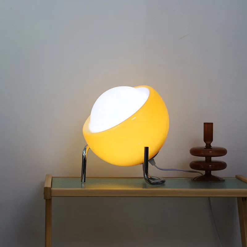 Contemporary egg-shaped glass table lamp in luminous yellow with chrome stand on modern console beside decorative candlestick | Alinora